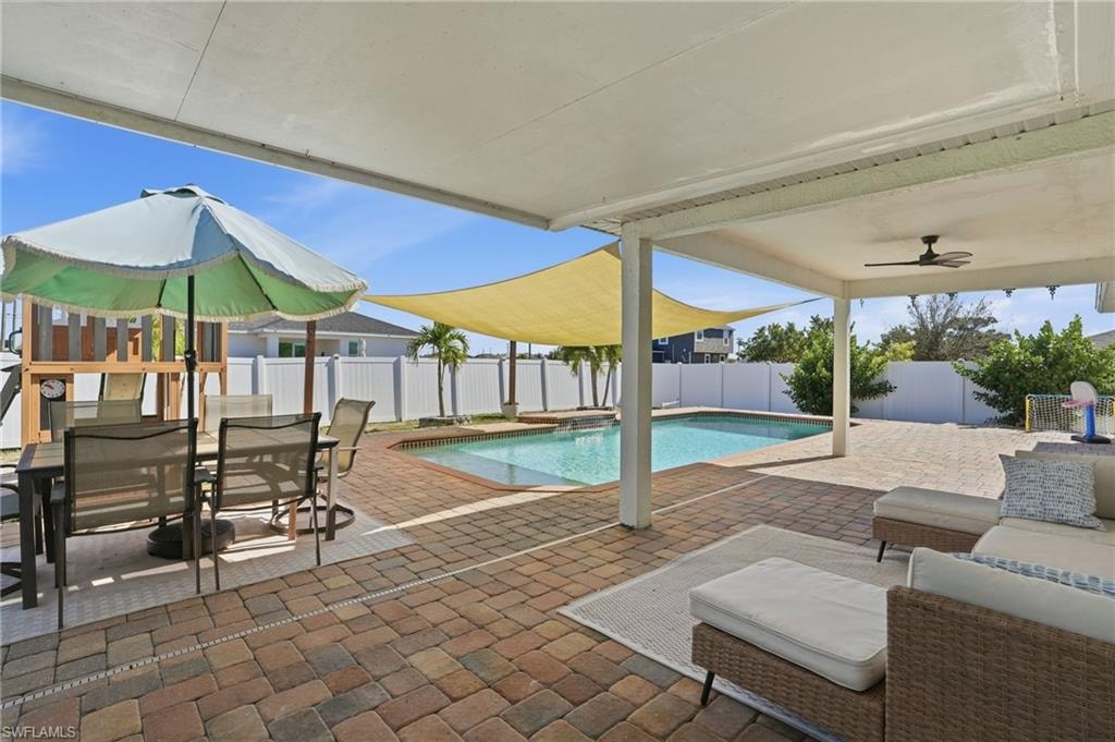 View of swimming pool with a patio, outdoor dining space, a fenced backyard, and a pool with connected hot tub