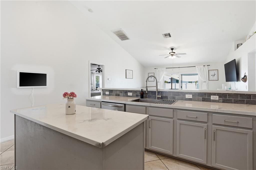 Kitchen with gray cabinetry, backsplash, lofted ceiling, ceiling fan, and dishwasher