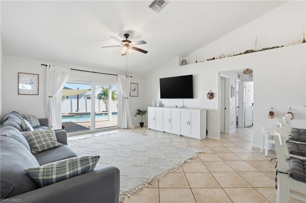 Living area with a ceiling fan, light tile patterned flooring, and high vaulted ceiling