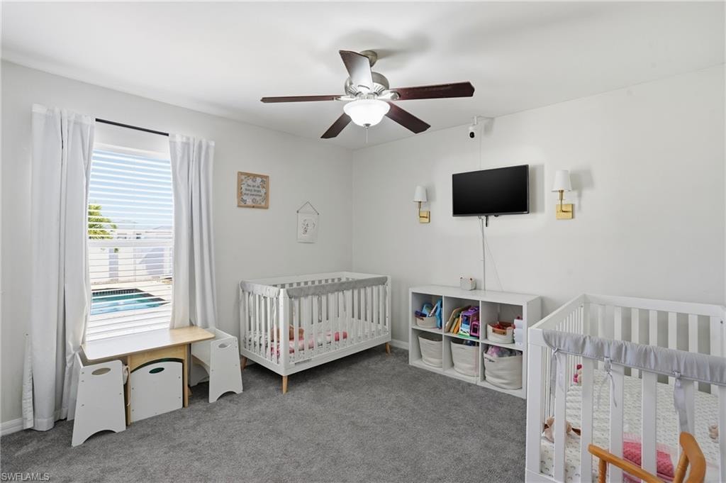Bedroom featuring a nursery area, carpet flooring, and a ceiling fan