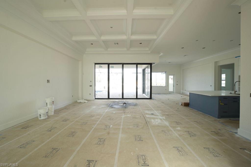 Unfurnished living room with coffered ceiling, beamed ceiling, and crown molding