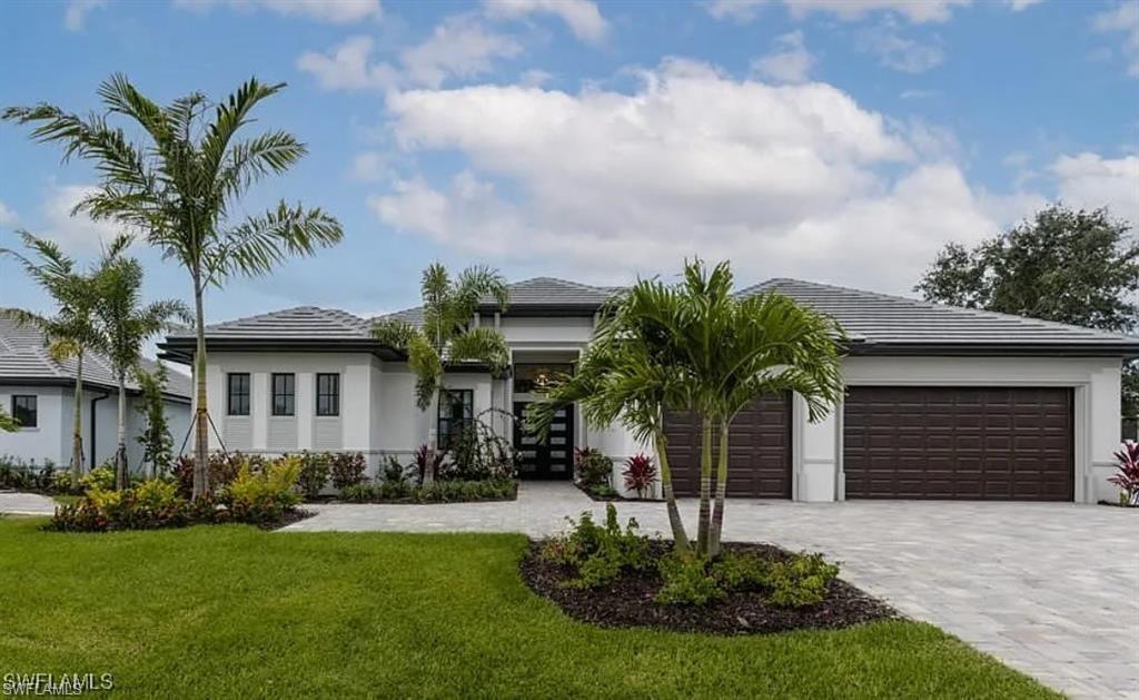 View of front of home with decorative driveway, a front lawn, stucco siding, and a tile roof