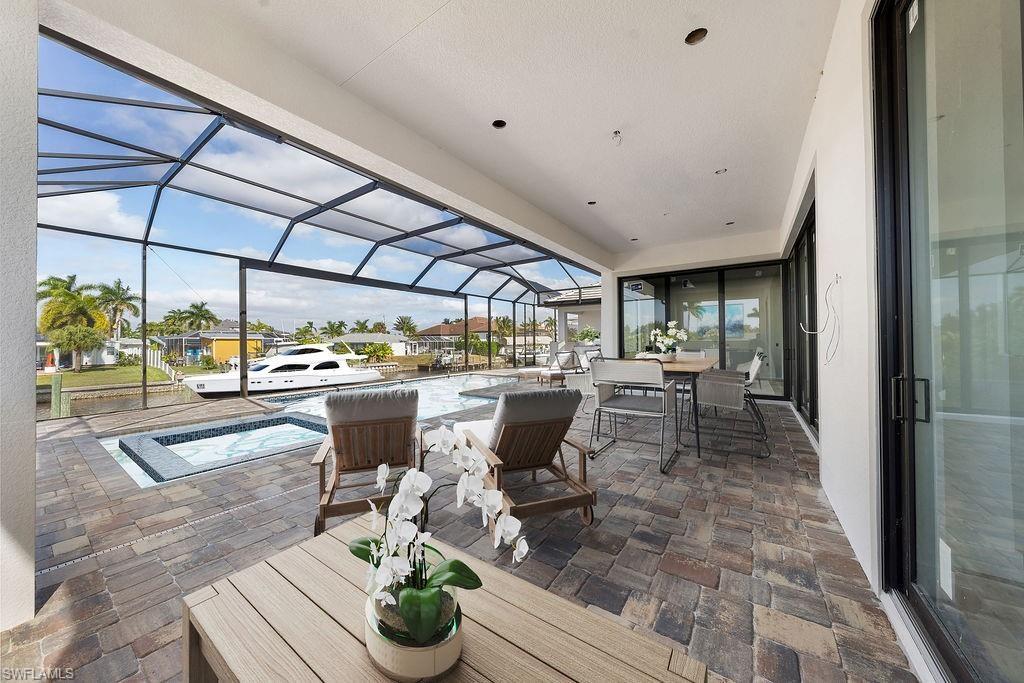 View of patio / terrace featuring a sunroom, a lanai, an in-ground hot tub, and outdoor dining area