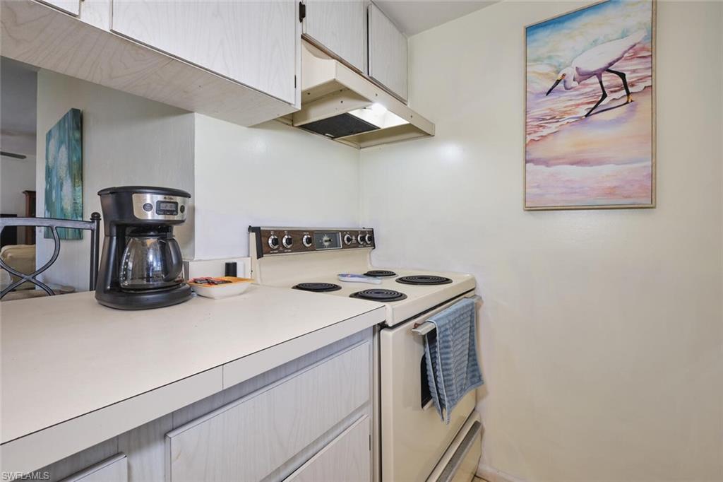 Kitchen featuring white range with electric cooktop, under cabinet range hood, and light countertops