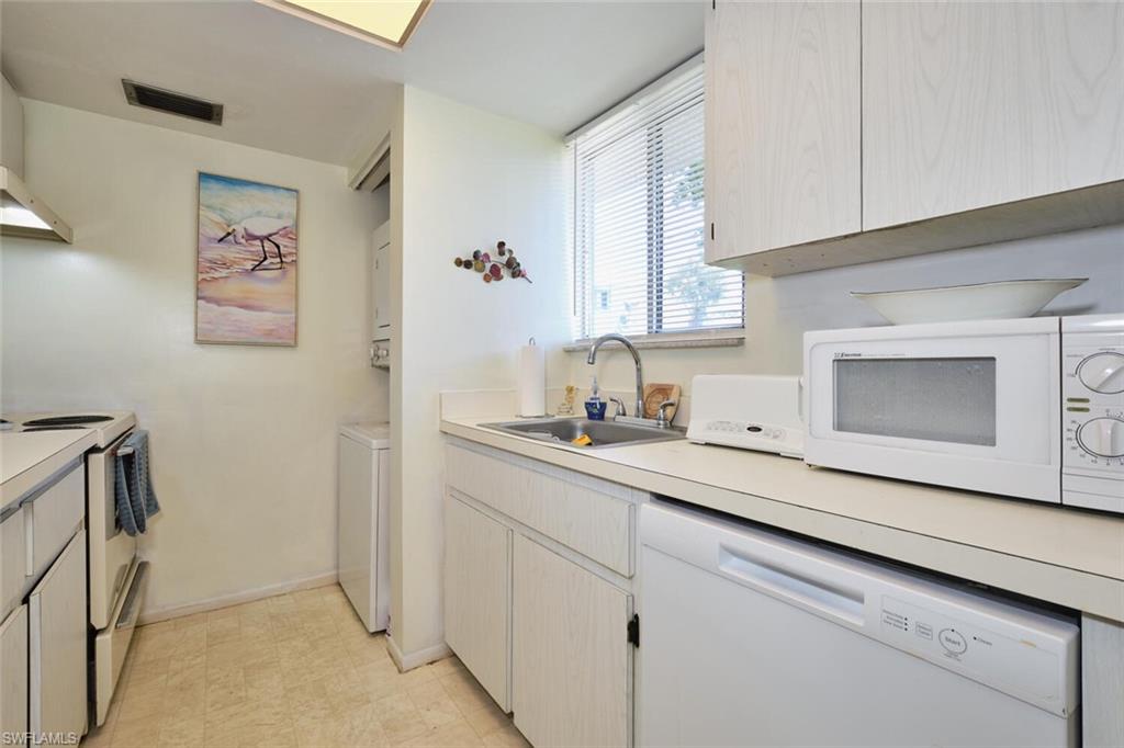 Kitchen featuring white appliances, a sink, light countertops, and baseboards