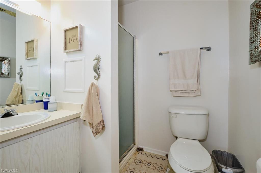 Full bath with toilet, vanity, a shower stall, and baseboards