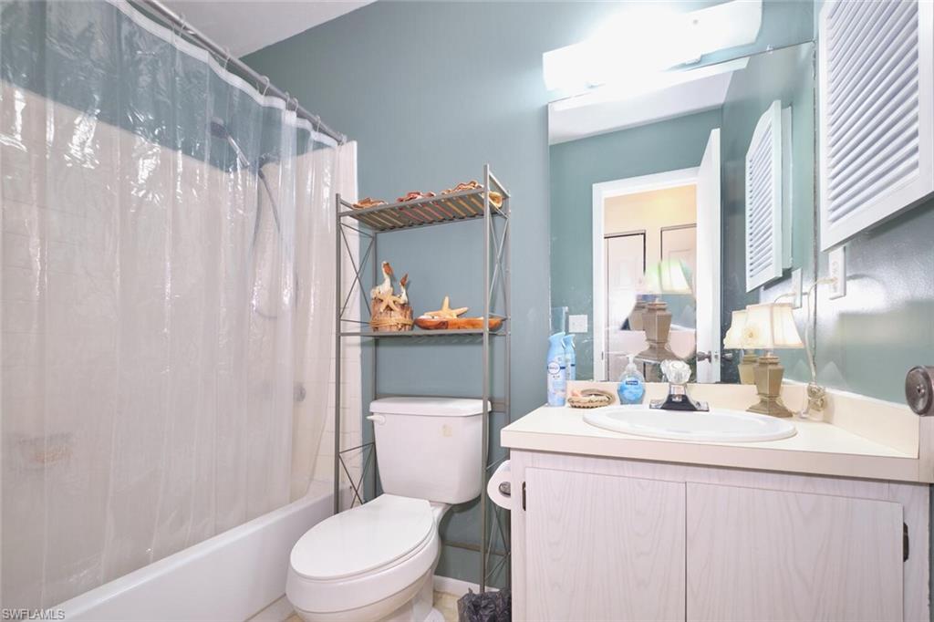 Bathroom featuring vanity, shower / bath combo, and toilet