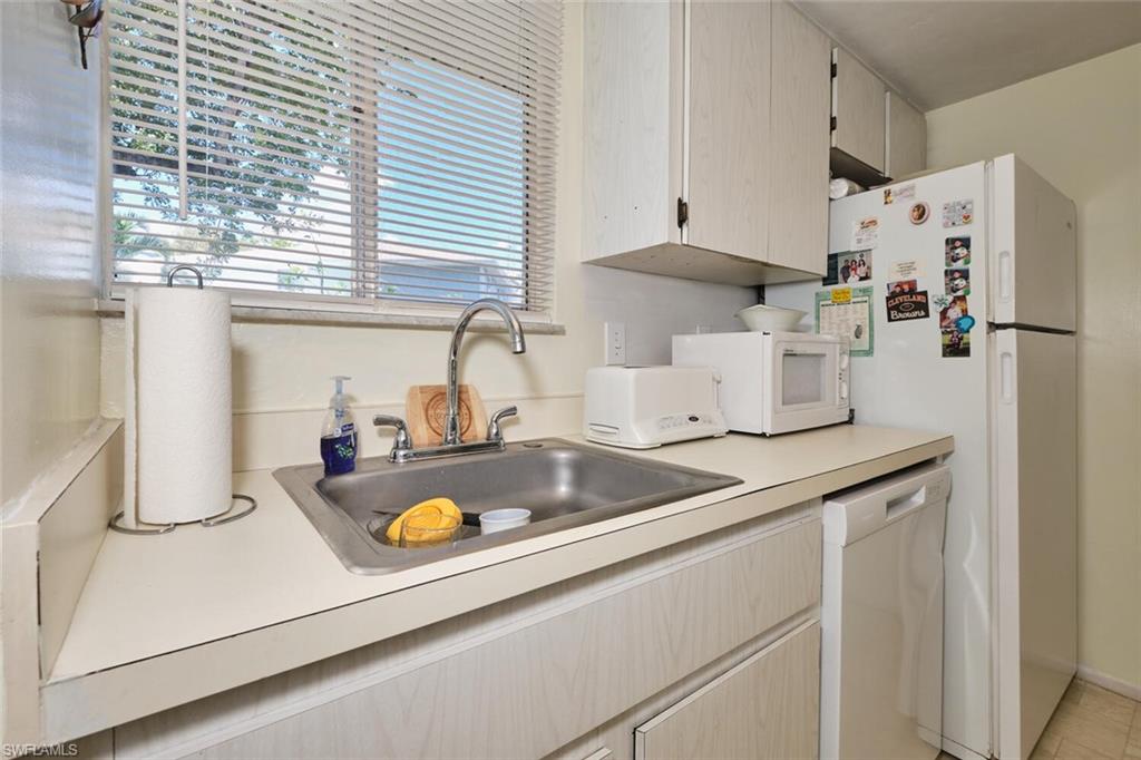 Kitchen with white appliances, a sink, healthy amount of natural light, and light countertops