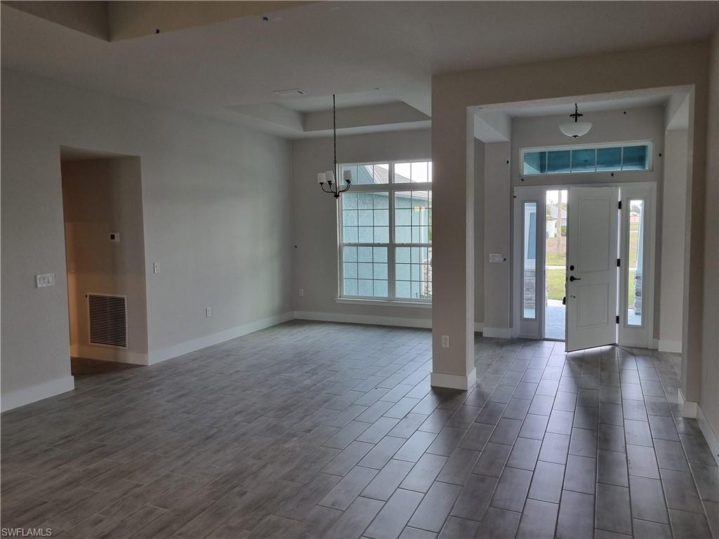 Entryway with wood tiled floors, a raised ceiling, and hanging lights