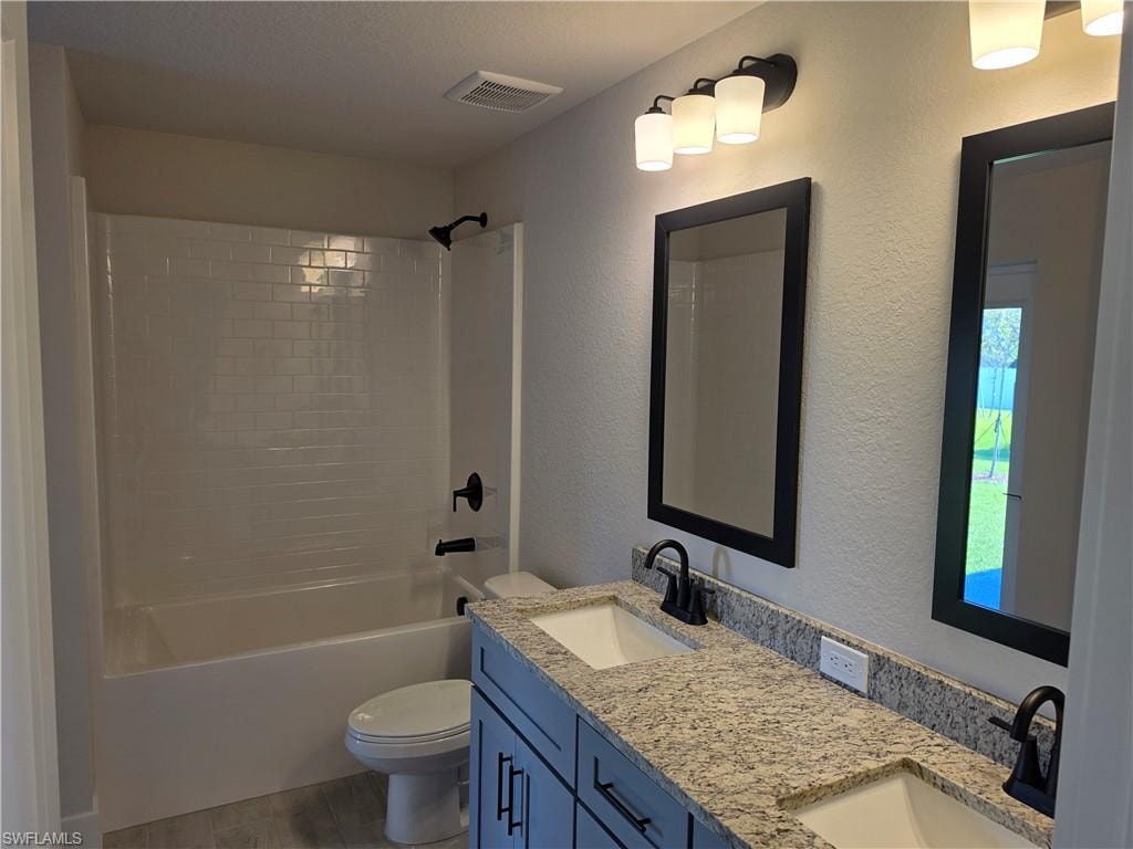 Bathroom featuring a dual vanity with light-toned granite countertops, undermount sinks, and matte black fixtures