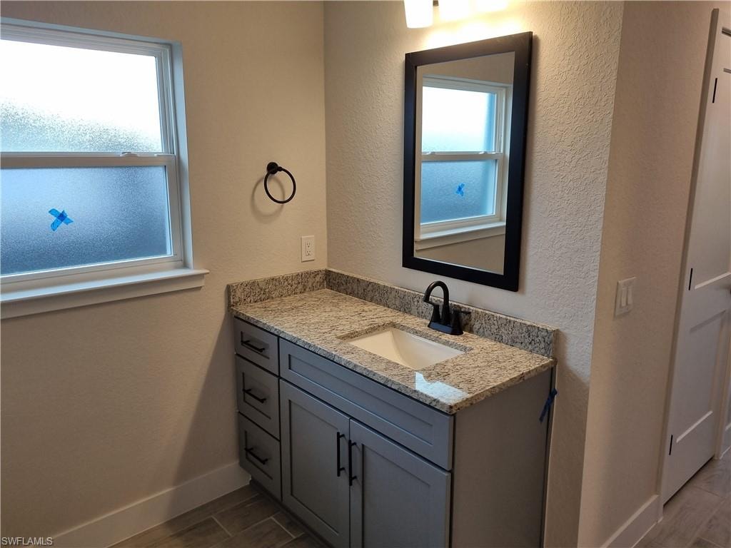 Bathroom with a textured wall, vanity, and wood finish floors