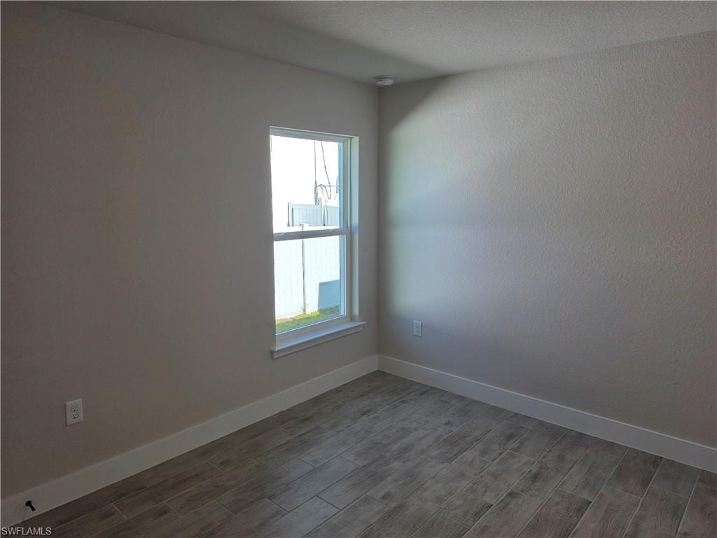 Room featuring wood-finish tile flooring, a single window with white trim, light neutral wall paint, and recessed ceiling lighting
