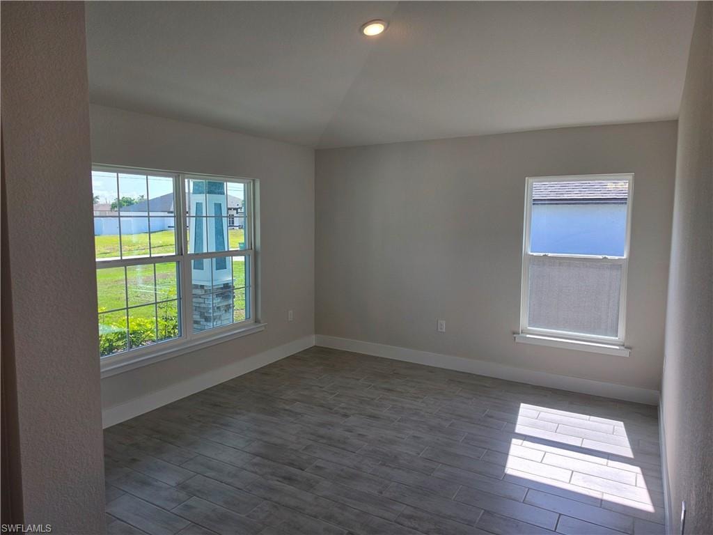 Spacious room featuring wood-finish tile flooring, recessed ceiling lighting, and two windows providing abundant natural light