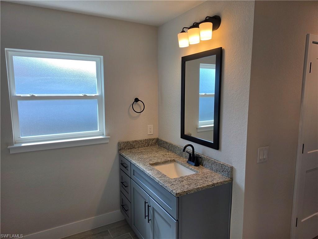 Bathroom vanity featuring a stone countertop, an undermount sink, and matte black hardware