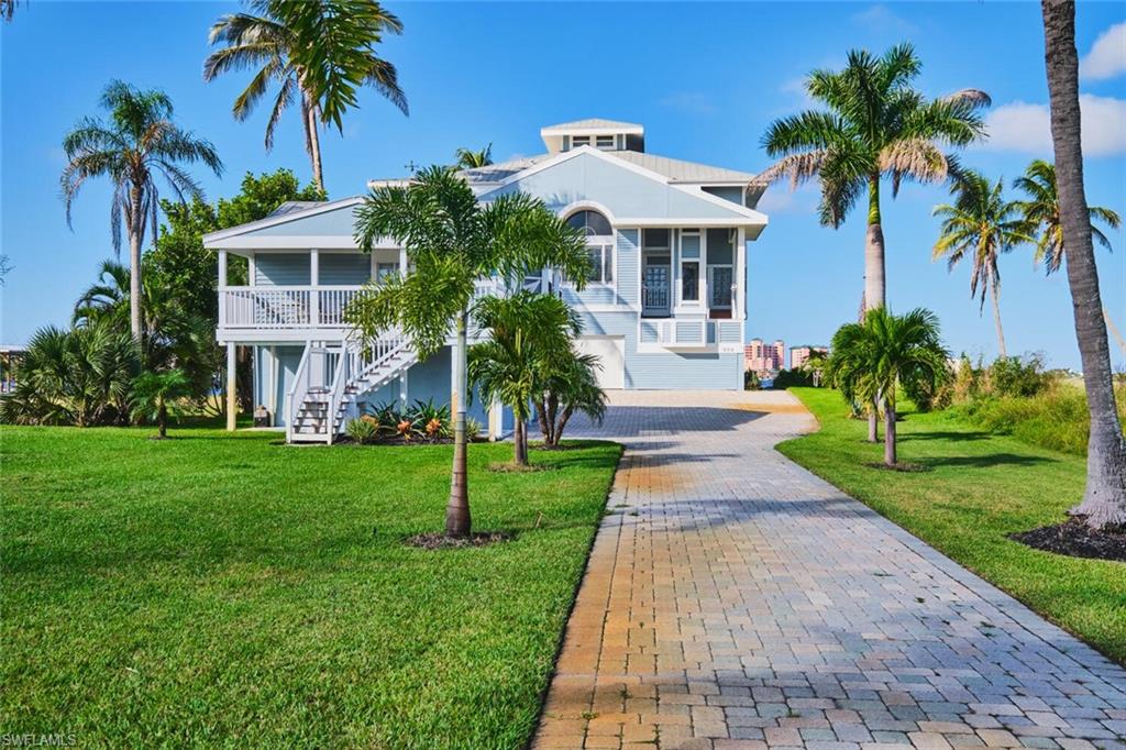 Beach home with stairs, a front lawn, and decorative driveway