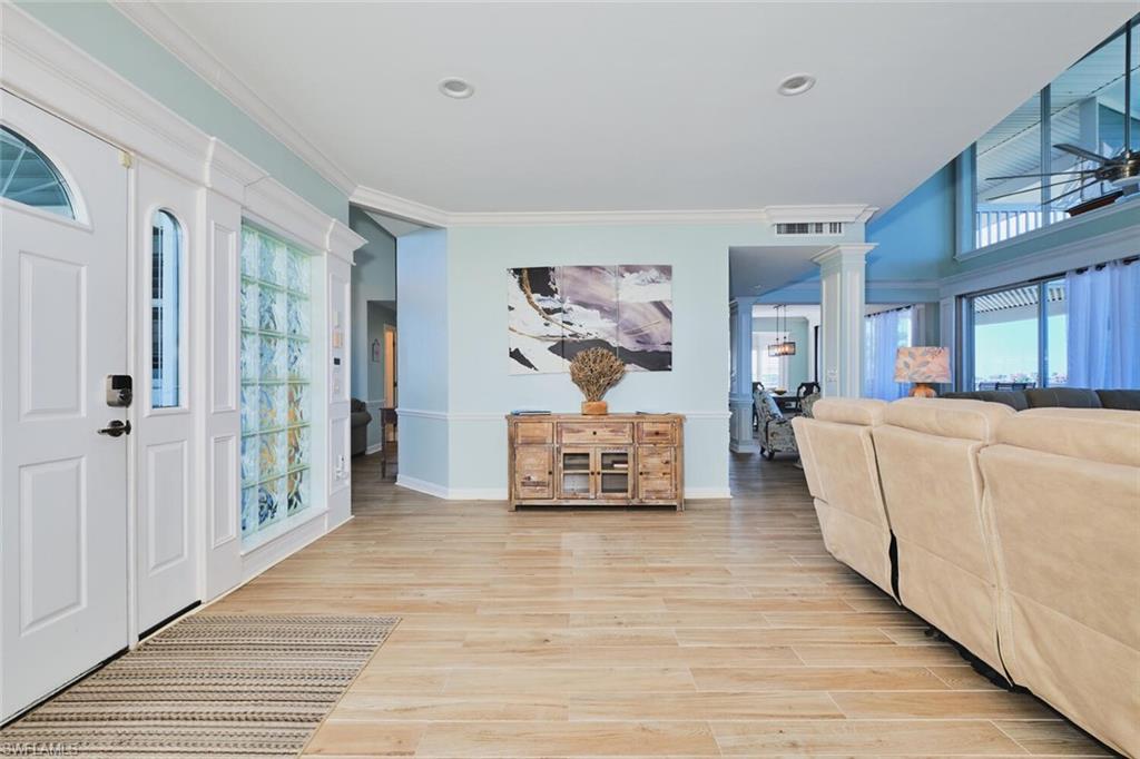 Foyer with ornate columns, plenty of natural light, light wood-style floors, crown molding, and recessed lighting