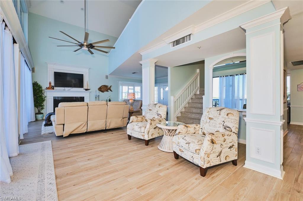 Main Living room with ornate columns, a high ceiling, ceiling fan, light wood-style floors, and a fireplace