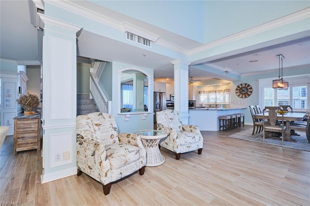 Main Living area featuring stairway, crown molding, light wood-type flooring, and decorative columns