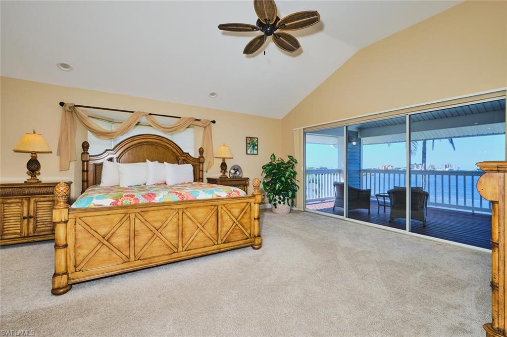 Master Bedroom on 3rd Floor - with views of bay and Gulf - featuring carpet flooring, a ceiling fan, vaulted ceiling, and access to exterior