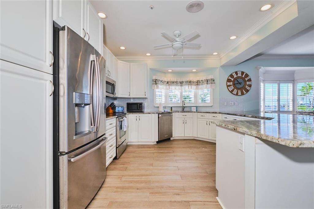 Main Kitchen featuring appliances with stainless steel finishes, white cabinets, light stone countertops, decorative backsplash, and recessed lighting