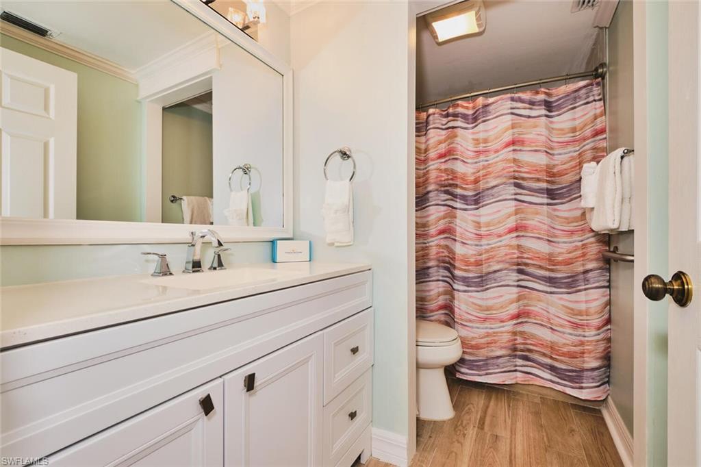 Main living area Full bath with vanity, light wood finished floors, and ornamental molding