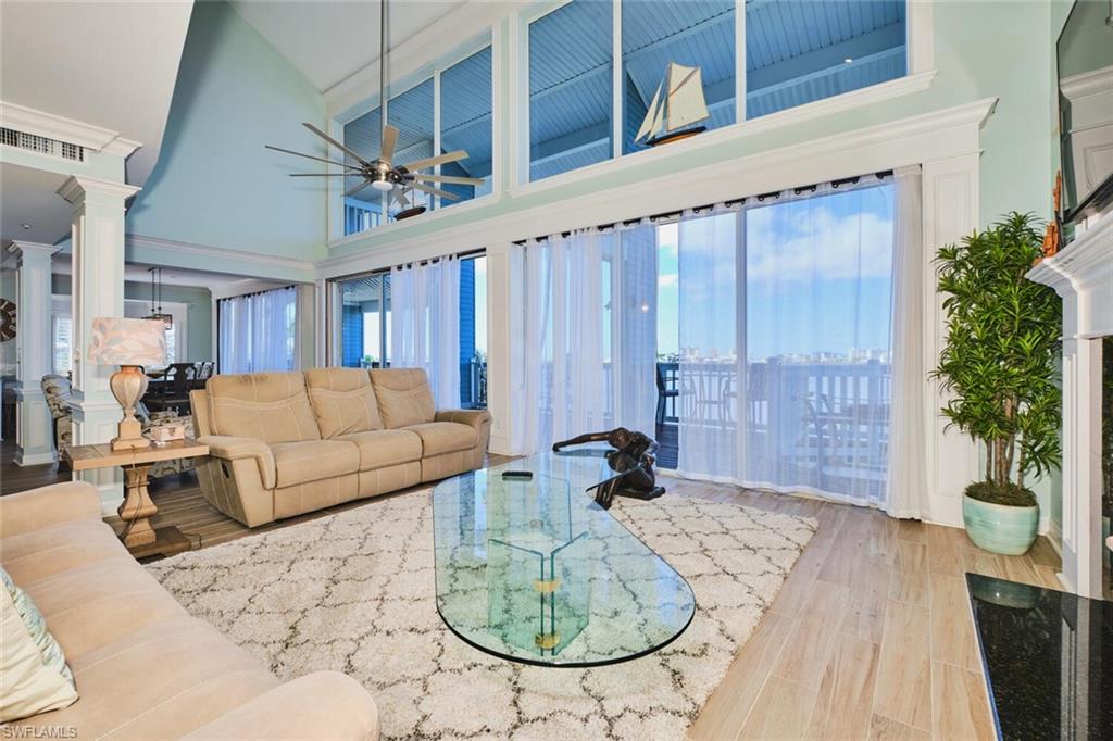 Main Living area with a towering ceiling, wood finished floors, a ceiling fan, and ornate columns