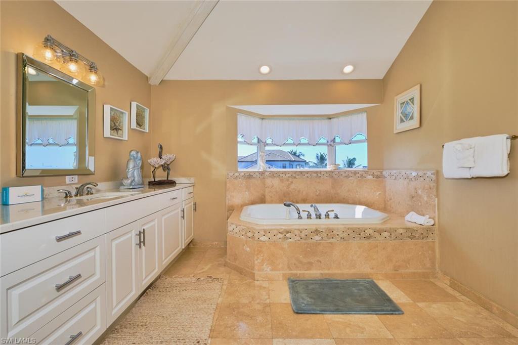 Bathroom featuring a garden tub, vanity, beamed ceiling, light tile patterned floors, and recessed lighting