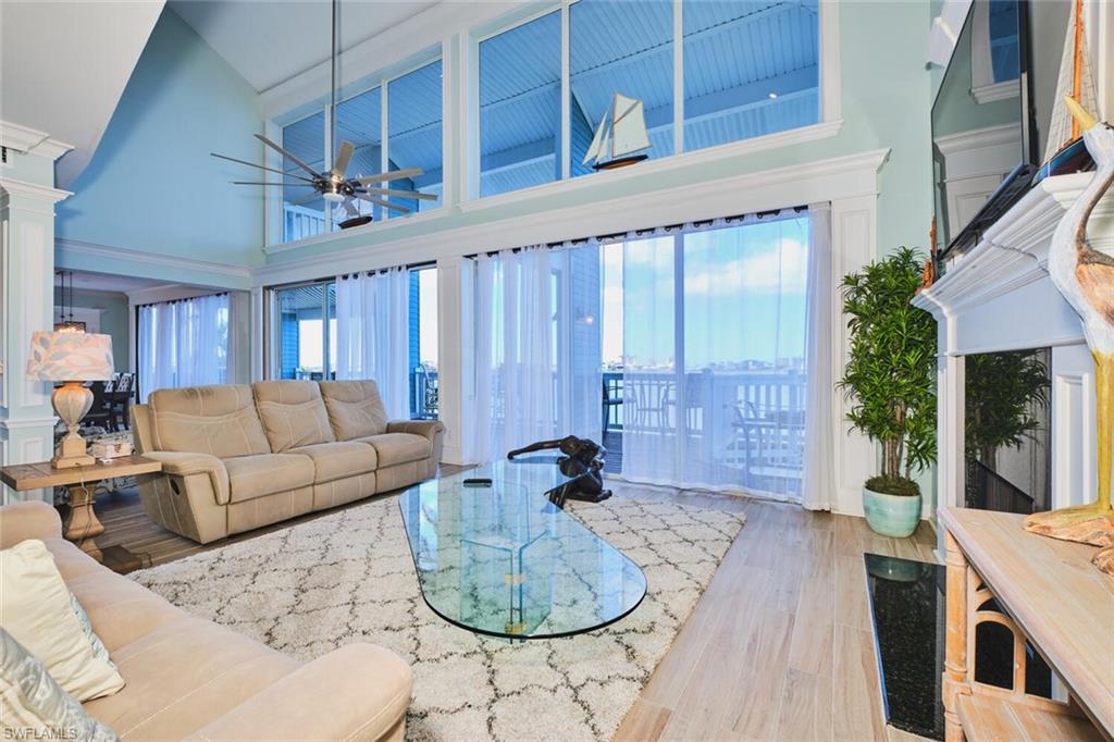 Main Living area with a towering ceiling, wood finished floors, healthy amount of natural light, ceiling fan, and ornate columns