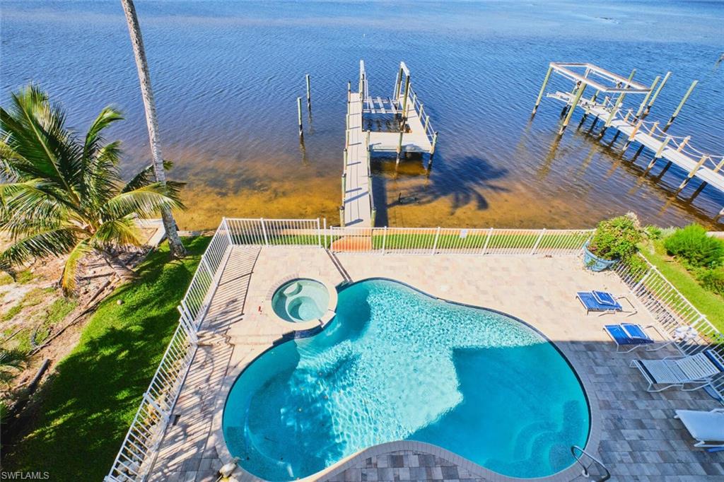View of pool with an in-ground hot tub, a patio area, a water view, and boat lift