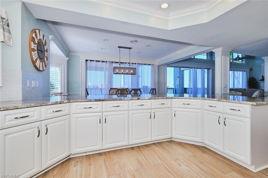 Main Kitchen with crown molding, white cabinets, light stone counters, plenty of natural light, and recessed lighting