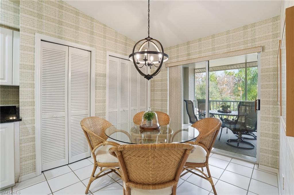 Dining area featuring wallpapered walls, light tile patterned floors, and a chandelier