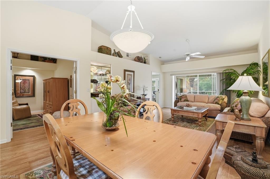 Dining room with a ceiling fan, light wood-style flooring, and high vaulted ceiling