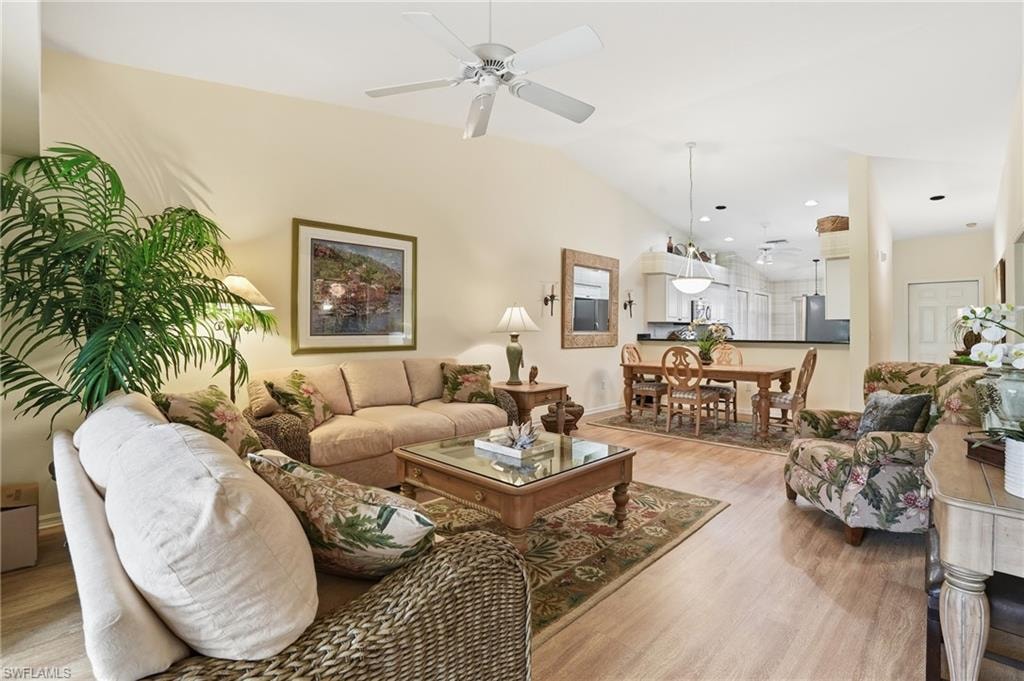 Living area with wood finished floors, vaulted ceiling, a ceiling fan, and recessed lighting