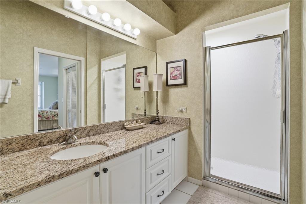 Bathroom featuring vanity, connected bathroom, a shower stall, and light tile patterned floors