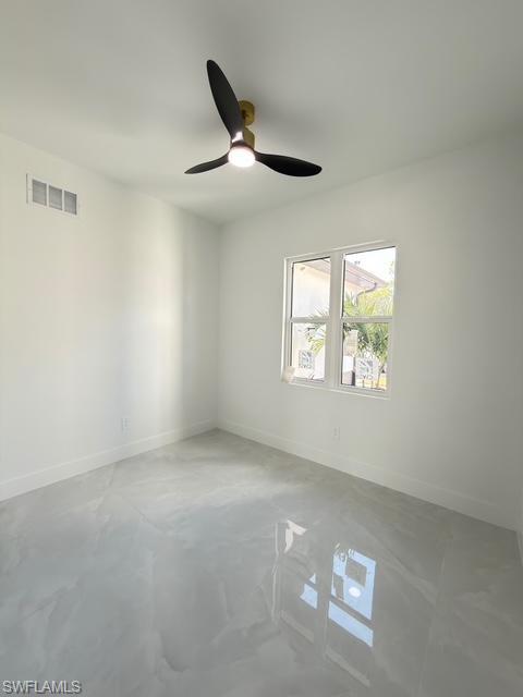 Spare room featuring a ceiling fan and concrete floors