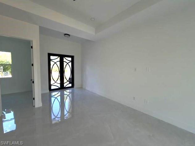 Spare room with french doors, a tray ceiling, and finished concrete floors