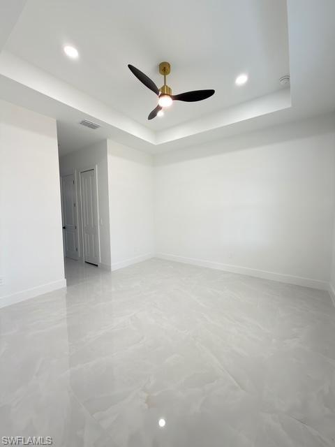Empty room featuring recessed lighting, a tray ceiling, and a ceiling fan