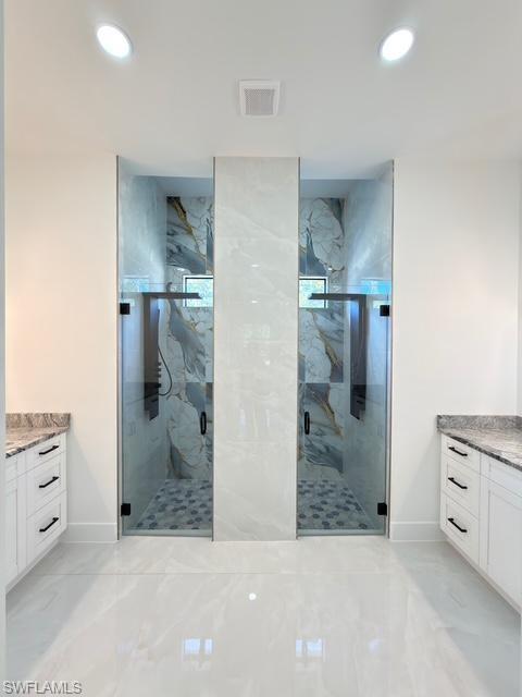Bathroom with vanity, a marble finish shower, recessed lighting, and light marble finish flooring