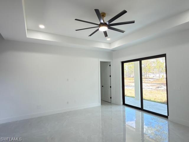 Empty room with a tray ceiling, recessed lighting, a ceiling fan, and finished concrete flooring