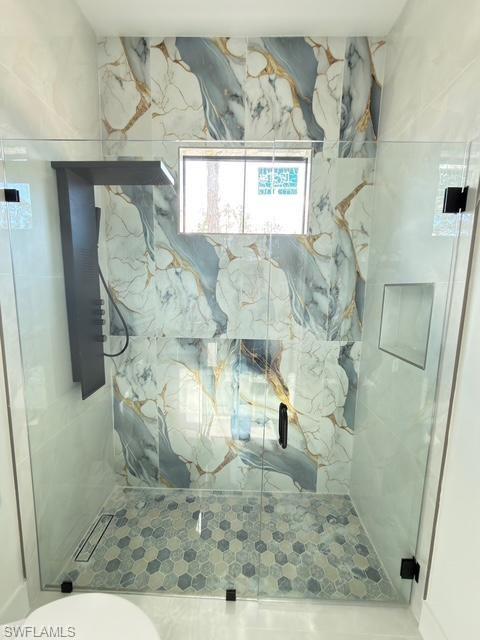 Full bathroom with a marble finish shower