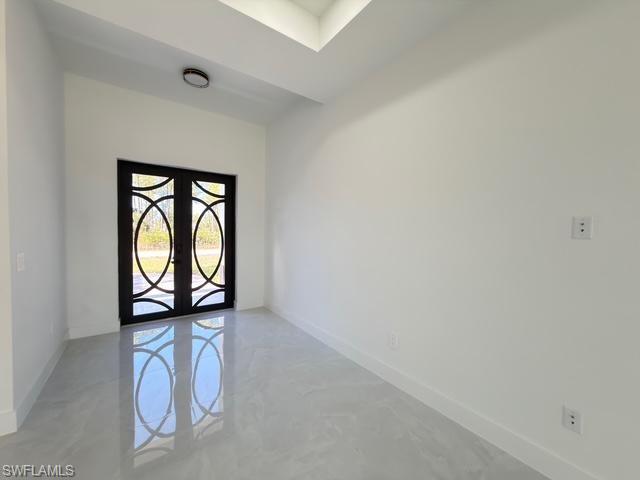 Spare room featuring french doors and concrete floors