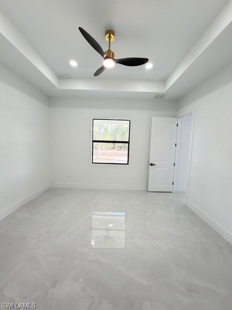 Empty room featuring a tray ceiling, a ceiling fan, and recessed lighting