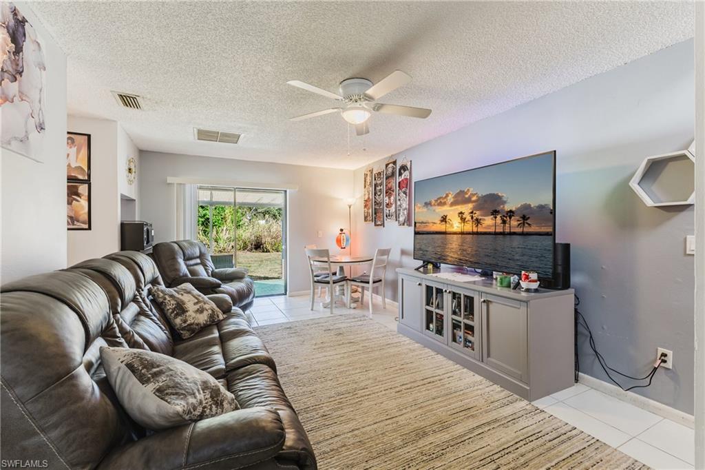 Living area featuring light tile patterned floors, a textured ceiling, and a ceiling fan