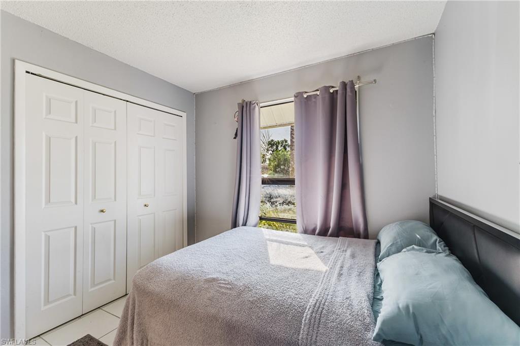 Tiled bedroom with a textured ceiling and a closet
