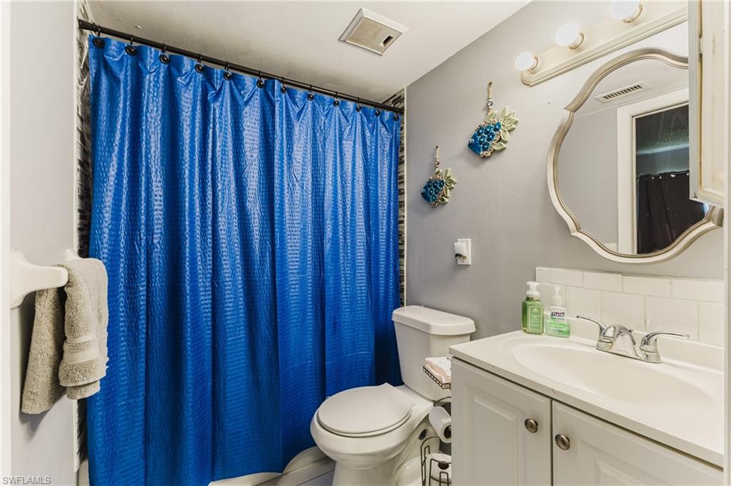 Full bath with a shower with curtain, decorative backsplash, and vanity