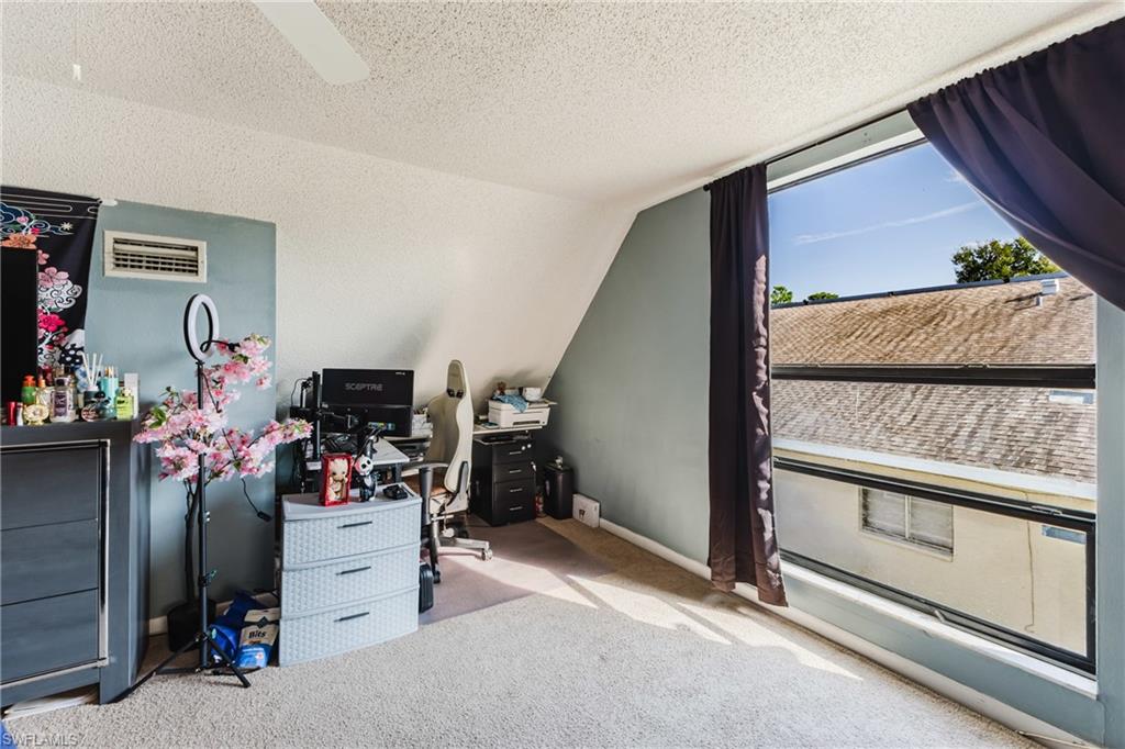 Office with light carpet, lofted ceiling, and a textured ceiling