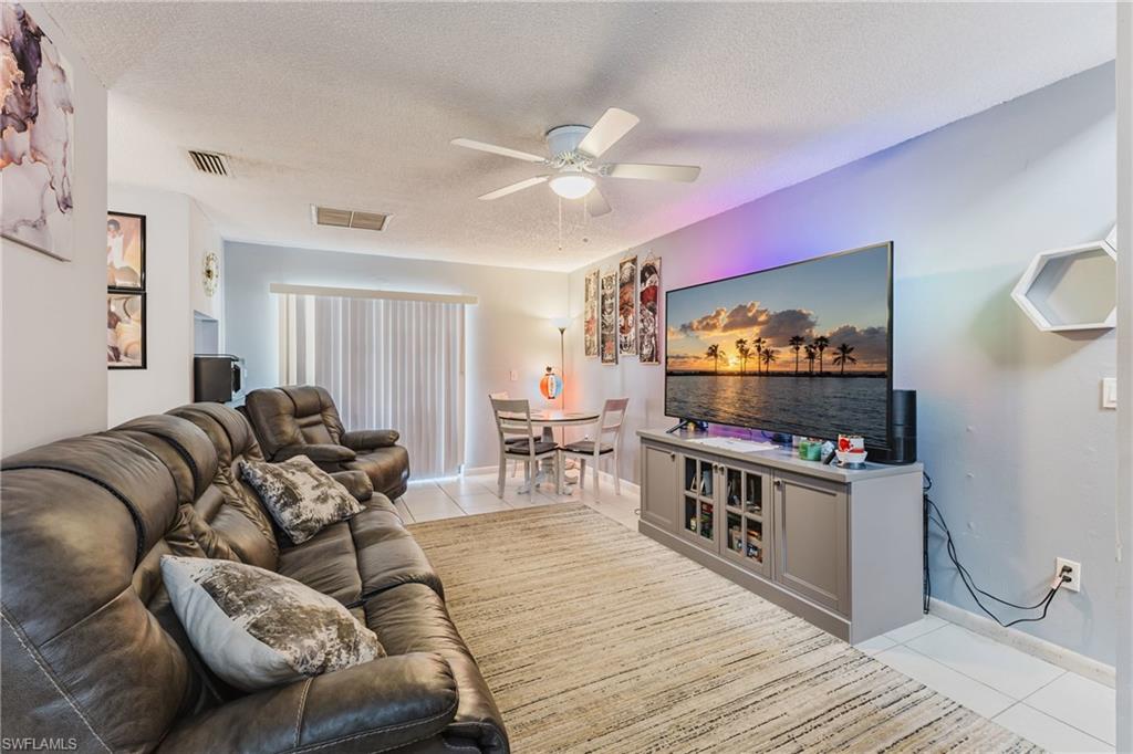 Living room with light tile patterned floors, a textured ceiling, and a ceiling fan