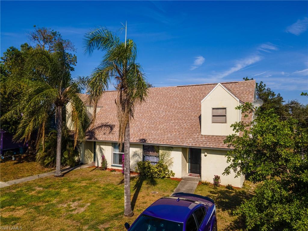 Cape cod home with stucco siding, roof with shingles, and a front lawn