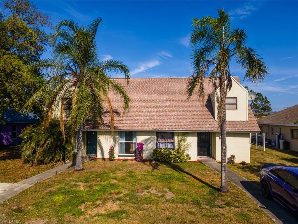 View of front of property with a shingled roof, a front yard, and stucco siding
