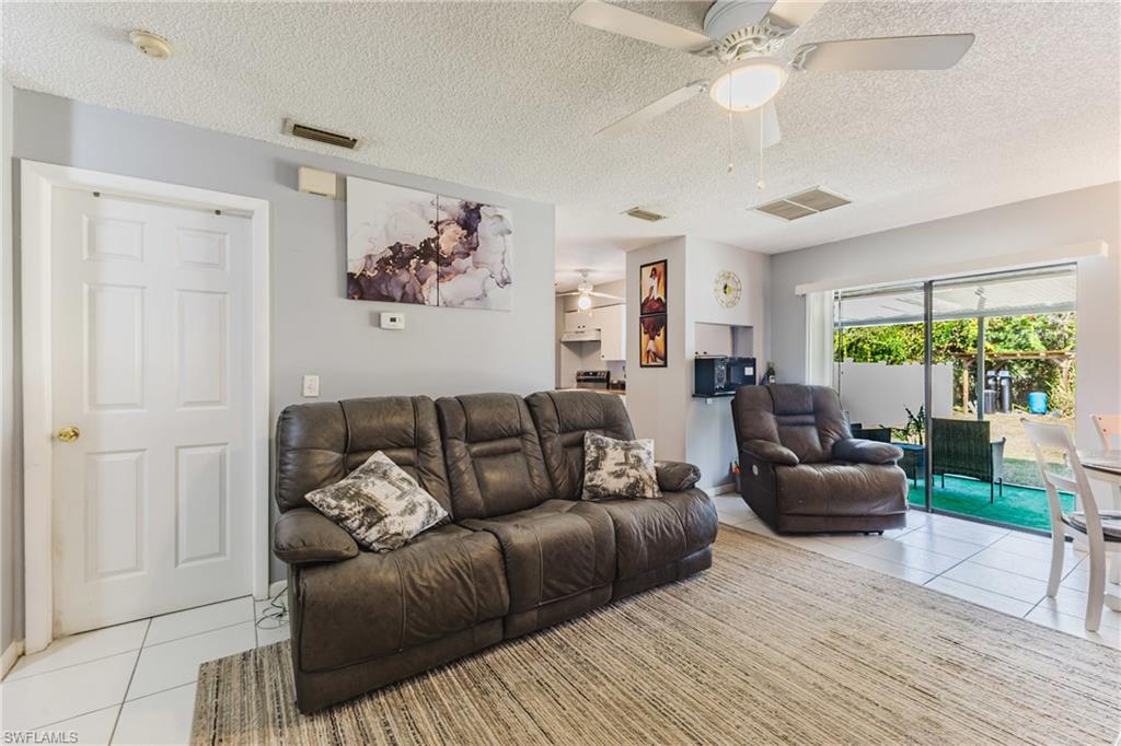 Living room with light tile patterned flooring, a textured ceiling, and ceiling fan